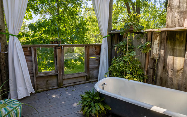 Private outdoor bathtub surrounded by greenery at a Northwest Indiana vacation home